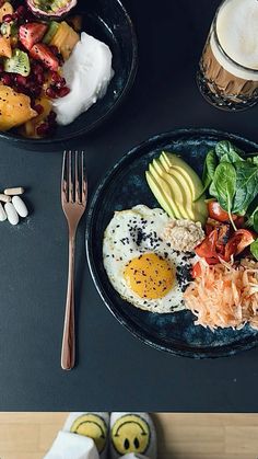 two plates filled with different types of food on top of a black table next to each other