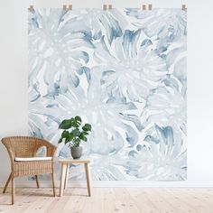 a chair sitting next to a potted plant on top of a wooden table in front of a blue and white wall