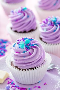 cupcakes with purple frosting and sprinkles on a plate