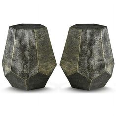 two black vases sitting next to each other on a white surface, one is made out of metal