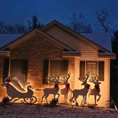 lighted reindeers and sleigh in front of a house