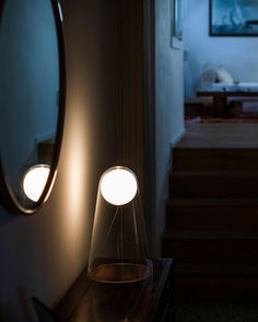 two lights are on in the corner of a room next to a mirror and stairs