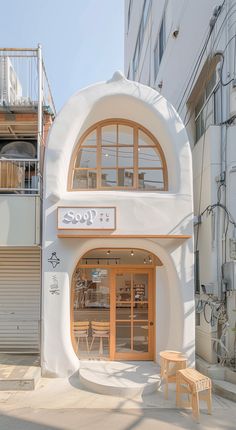 a white building with an arched window and wooden bench in front of it on the sidewalk