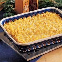 a casserole dish with corn and cheese in it sitting on a table next to pine branches