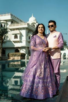 a man and woman standing next to each other near a pool in front of a building