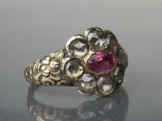 "Well this is just one of those rarities that doesn't come along very often! A later Georgian foil-backed natural pink sapphire and rose cut diamond ring with a floral band circa 1820. This ring originally had black enamel in the recessed areas of the band with traces of it still visible today. The rose cuts are very sparkly but with a dark sparkle, several of these stones would be considered fancy-color light brown (this is not due to the foil color, but the color of the diamond). There is no m Victorian Ruby Ring With Single Cut Diamonds, Antique Pink Rose Cut Diamond Jewelry, Victorian Pink Ruby Ring For Anniversary, Victorian Pink Rose Cut Diamond Jewelry, Antique Pink Jewelry With Rose Cut Diamonds, Pink Victorian Ruby Ring For Anniversary, Antique Pink Ruby Ring, Antique Pink Ruby Ring With Rose Cut Diamonds, Pink Hallmarked Victorian Ruby Ring