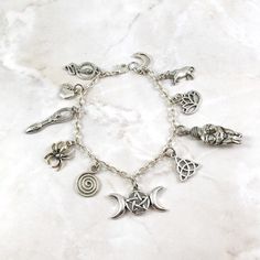 This fun, goddess themed charm bracelet is the perfect accessory to showcase your love for the divine feminine in a subtle way. All charms chosen for this design are symbols associated with goddesses from around the world.Charms included:SnakeAppleCeltic Goddess SymbolSpiderSpiralTriple Goddess SymbolTriquetaVenus of WillendorfLotusCowCrescent MoonAvailable in both an adult and child size. Adult size bracelet measures about 7.5 inches in length. Child size measures about 6.5 inches. Extra jump r Spiritual Charm Bracelet With Dangling Charms, Silver Spiritual Charm Bracelet For Meditation, Spiritual Nickel-free Dangle Charm Bracelet, Spiritual Silver Charm Bracelet For Meditation, Handmade Spiritual Charm Bracelet, Spiritual Metal Charm Bracelet With Dangle, Goddess Feminine, Triple Goddess Symbol, Greek Mythology Jewelry