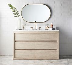 a bathroom vanity with a round mirror above it and a white tiled wall behind it