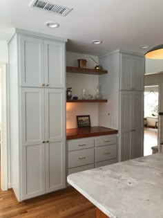 an empty kitchen with white cabinets and wood flooring on the walls, along with a marble counter top