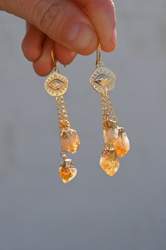 Stunning Citrine evil eye earrings to remind you to be your own light! These beauties are perfect day-to-day earrings you can rock for that extra unique touch with any outfit. The Citrine with gold is elegant and feels so rich in good vibes! Citrine is a Solar Plexus Chakra gemstone that aligns your energy to be in your power and to stand fully in your light. Also available in Amethyst & Quartz. Pair with our Citrine Lariat in gold. Citrine gemstones with gold detailing hanging from a gold prote Be Your Own Light, Lighting The Way, Protective Eye, Gold Lariat Necklace, Angel Aura Quartz, Citrine Earrings, Evil Eye Earrings, Chakra Jewelry, Quartz Jewelry