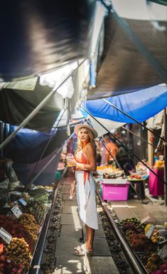 a woman standing on train tracks in an outdoor market