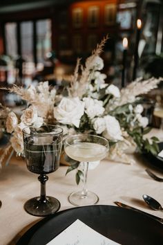 the table is set with an elegant centerpiece and wine glasses, silverware, and flowers