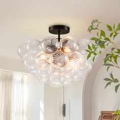 a modern light fixture hanging from the ceiling in a room with white walls and windows