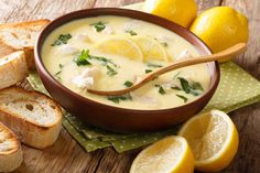 a bowl of soup with bread and lemons