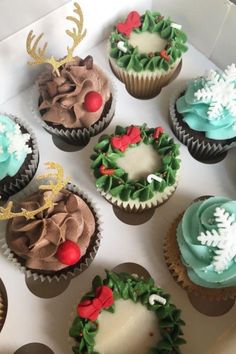 twelve decorated cupcakes in a box with frosting and christmas decorations on them