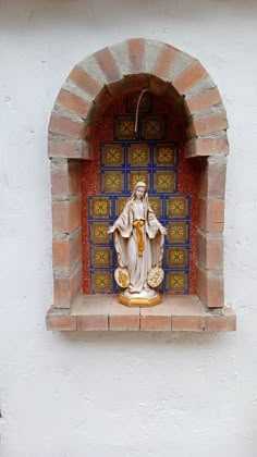 a statue of jesus in a window with blue and yellow tiles on the outside wall