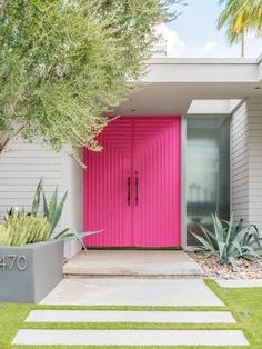 a pink door in front of a house with steps leading up to it and plants on either side