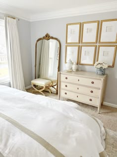 a white bed sitting next to a dresser with a mirror on it's side