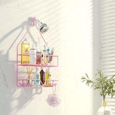 a pink shelf with bottles and soaps on it in a white tiled room next to a potted plant