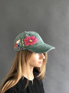 a woman wearing a green hat with pink flowers on the brim and side view