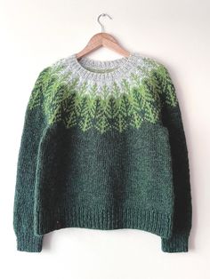 a green and white sweater hanging on a wooden hanger