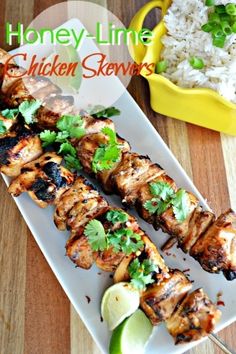 chicken skewers on a plate with rice and cilantro garnish