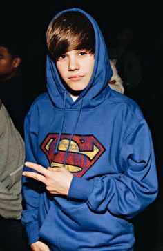 a young man wearing a superman hoodie standing next to another person in the dark