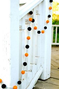 orange and black pom - poms are strung on the front porch railings