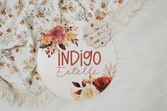 a sign that says indigoo esttelle with flowers on it next to a white blanket