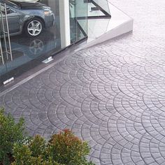 a car is parked in front of a building with glass doors and circular tiles on the ground