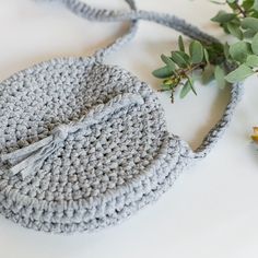 a crocheted purse sitting on top of a white table next to a plant