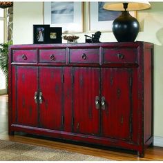 a red cabinet with two doors and three drawers on top of it next to a lamp