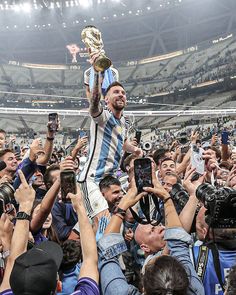 a man holding up a trophy surrounded by fans