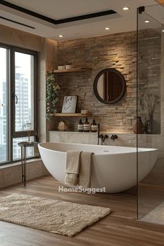 a bathroom with a large white bathtub sitting next to a tall glass window and wooden flooring