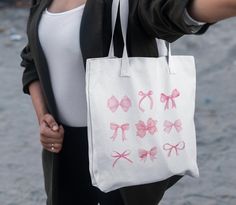 a woman holding a white bag with pink bows on it