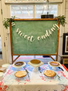 a table topped with pies next to a green chalkboard that says sweet ending