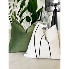 three pillows sitting on top of a white couch next to a green potted plant