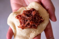 a hand holding a piece of food in it's palm, with meat on top