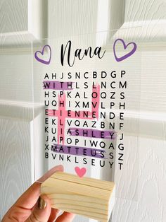 a hand holding a piece of wood with the word mama spelled in purple and pink