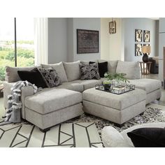 a living room with a large sectional couch and coffee table in front of a window