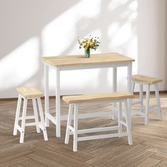 three stools and a table in a room with white walls, hardwood floors and parquet flooring