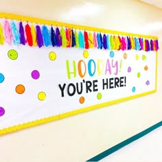 a bulletin board that says hooray you're here with colorful tassels on it