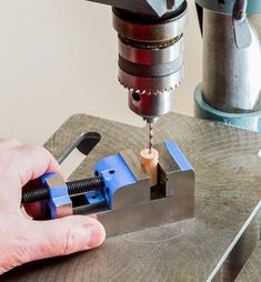 a man is using a drill to cut wood with a machine tool on a table