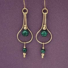 earrings with green beads hanging from them on a purple surface