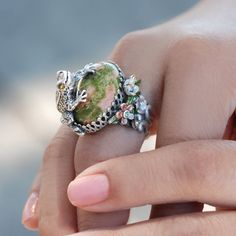 "This frog, just out of the tadpole stage, clambers onto a large epidote gemstone cabochon. A vintage crown setting and small sculptured flowers are fused to the adjustable pierce work band shank. The frog and the flowers are original sculptures of our studio. Fine detail features the texture of froggy's skin and toes and the levels of the clingy flowers. More art than whimsy. Layered in .925 silver. Size: 1.25\" x 1.25\". Adjustable ring for sizes 6 to 9. Entirely produced at Sweet Romance, our Bunny Rings, Frog Rings, Sugar Skull Ring, Frog Ring, Eye Rings, Frog Frog, Peacock Ring, Frog Jewelry, Peacock Jewelry