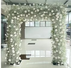 a white wedding arch decorated with flowers and greenery