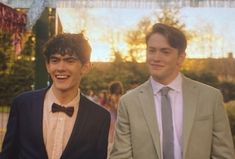 two young men wearing suits and bow ties standing next to each other in front of a crowd