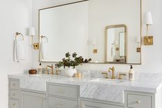 a bathroom vanity with two sinks and a large mirror above it, along with gold faucets