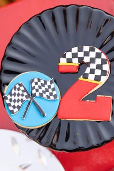 a paper plate with two decorated cookies on it and the number 2 in the shape of a checkered flag