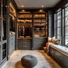 a large walk in closet with lots of drawers and clothes hanging on the walls, along with a bench